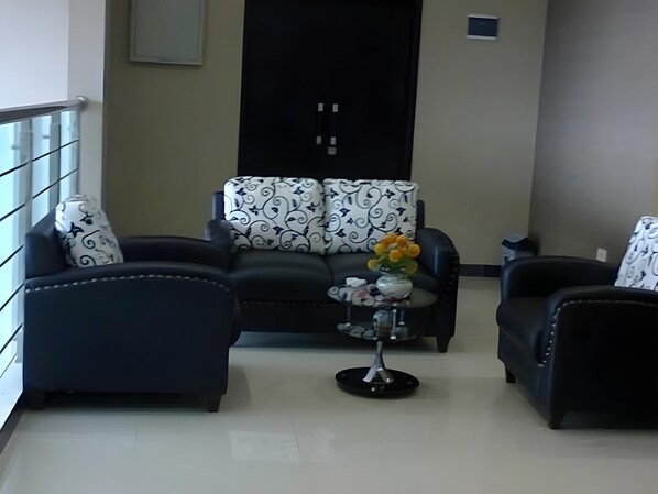 A living room with a sofa set, a coffee table, and a decorative vase with flowers.