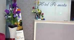 A reception desk with a sign reading 'Hotel Pemata' and a large floral arrangement to the left.