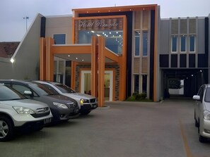 A building with a sign that reads 'Hotel Peninsula.' There are cars parked in front.
