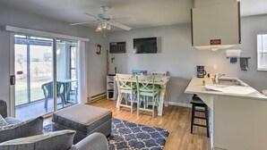 Un espacio habitable compacto con comedor, kitchenette y un amplio ventanal corredera que da a un patio exterior.