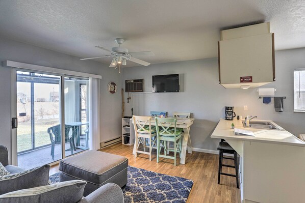 A compact living space with a dining area, kitchenette, and a large sliding glass door leading to an outdoor patio.