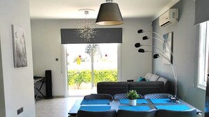 A modern dining area with a large table, four chairs, and a pendant light. - Villa Alba, Luxury 4 BDRM Villa with Heated Pool (Protaras)