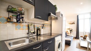 A modern kitchen with a built-in washing machine, a sink, and a countertop with various kitchen items. - Lovely & Independant - Queen size bed, netflix, wifi (Lourdes)