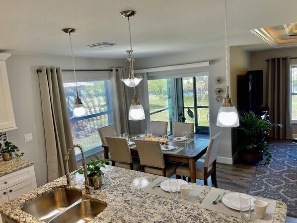 A modern kitchen with granite countertops, a stainless steel sink, and pendant lighting.