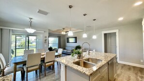 A modern kitchen with granite countertops, a built-in sink, and a dining area with a table and chairs. - Water Front Boundary Vacation Home Villa close to beaches, golfing, Fishing (Rotonda West)