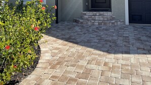 A residential house with a brick driveway, a dark front door, and a garage. - Water Front Boundary Vacation Home Villa close to beaches, golfing, Fishing (Rotonda West)
