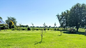 A grassy field with trees and a building with solar panels. - Apartment Peters by Interhome (Esens)