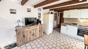 A compact kitchen with wooden cabinets, a built-in stove, and a TV. - Apartment Peters by Interhome (Esens)