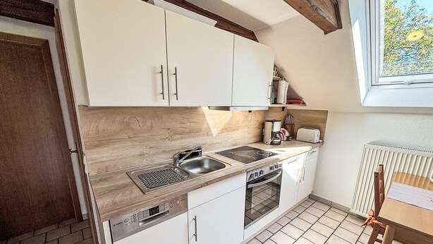 A compact kitchen with white cabinets, a built-in dishwasher, a stove, and a sink. - Apartment Peters by Interhome (Esens)