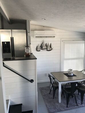 Eine moderne Küche mit einem Edelstahl-Kühlschrank, einem integrierten Wasserspender und einem Essbereich mit Tisch und Stühlen.