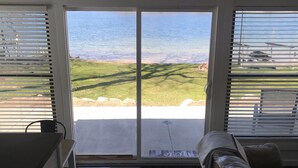 A room with a sliding glass door leading to a grassy area and a body of water. - Cozy Cottage on Baptist Lake Just North of G.R. (Sand Lake)