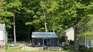 A lakeside cabin with outdoor seating and a dock. - Cozy Cottage on Baptist Lake Just North of G.R. (Sand Lake)