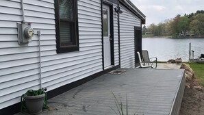 A house with a covered deck, a power outlet, and a potted plant. - Cozy Cottage on Baptist Lake Just North of G.R. (Sand Lake)