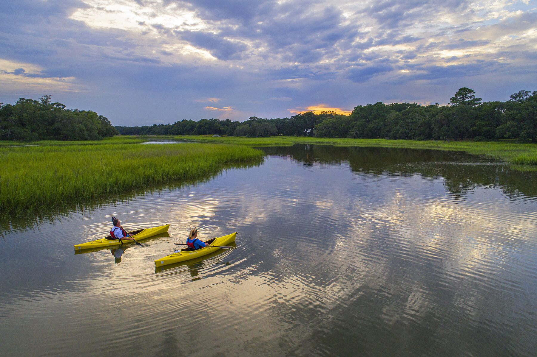 Deux kayaks sur une rivière paisible, entourés d’une végétation luxuriante.