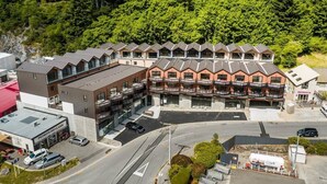 Ein mehrstöckiges Hotel mit einer Reihe von Balkonen, einem Parkplatz und einem angrenzenden Gebäude.