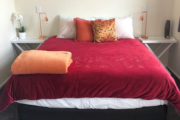 Main bedroom with queen bed, side tables and lamps.