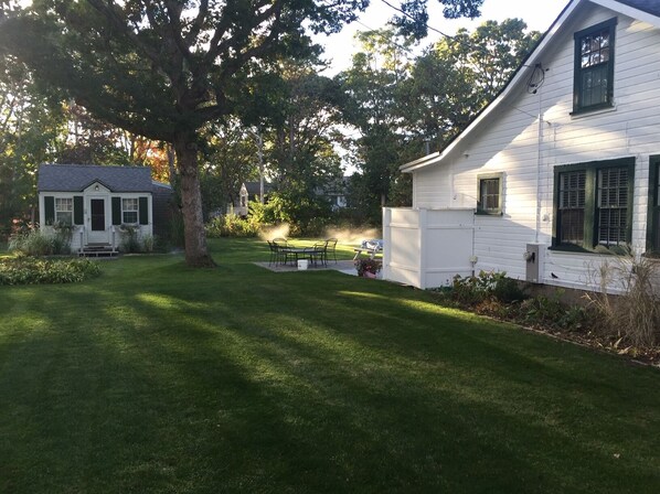 A white house with a lawn and a small shed.