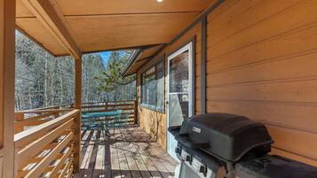 A wooden deck with a grill, a table, and chairs.