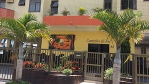 A hotel entrance with a red awning, palm trees, and a mural. - Apartamento de um Quarto (RJ)