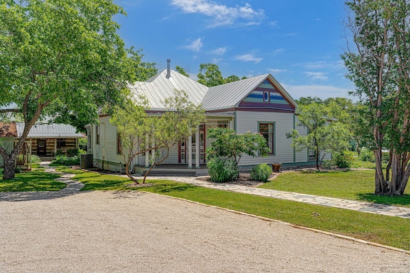 A two-story house with a covered porch, a well-maintained lawn, and a gravel driveway.