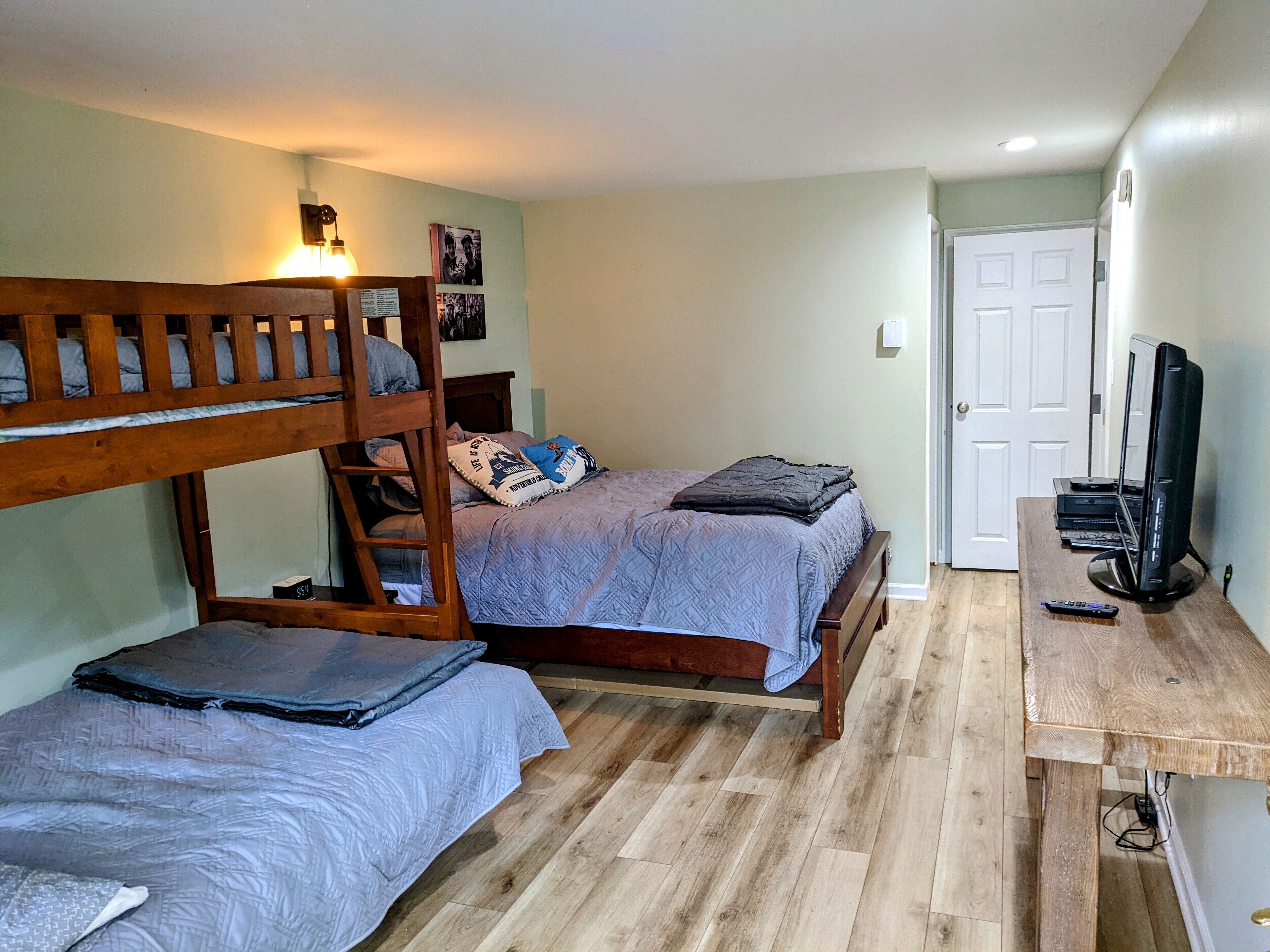 A bedroom with bunk beds, a desk, and a television.