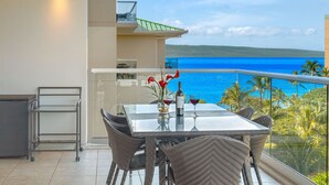 A balcony with a table set for two, overlooking a scenic ocean view.