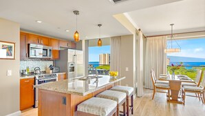A modern kitchen with a central island, stainless steel appliances, and a view of the ocean.