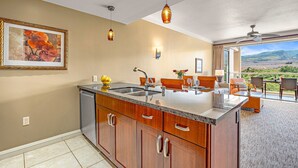 A kitchen with a large island, a dining area with a view, and a ceiling fan.