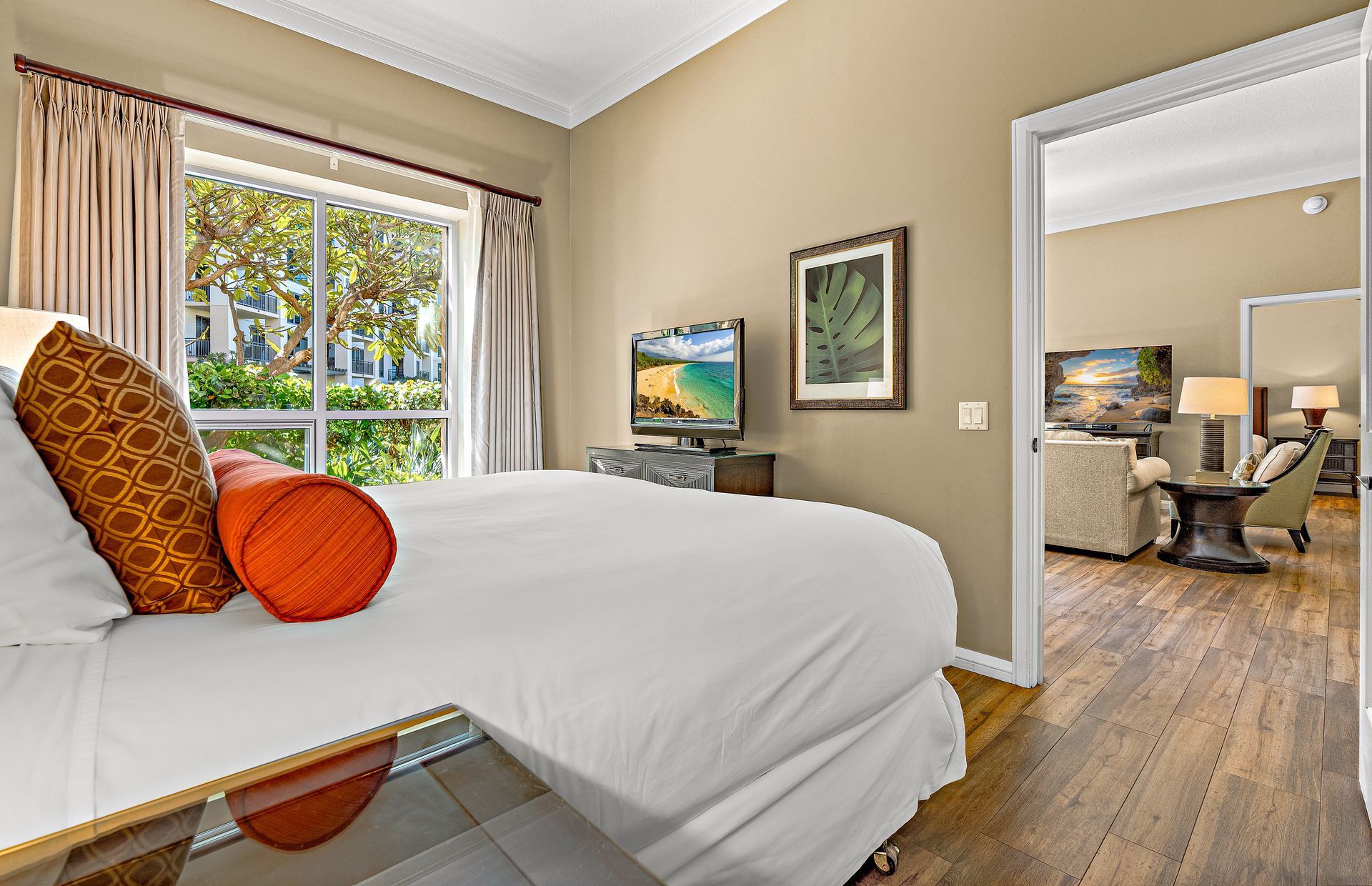 Ein Hotelzimmer mit einem großen Bett, einem Fernseher, einem Schreibtisch mit Stuhl und Blick ins Freie durch ein Fenster.