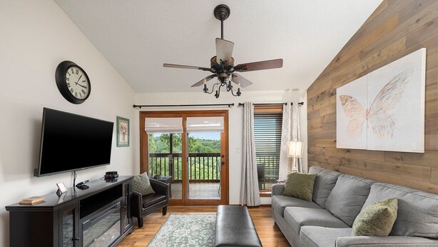 A modern living room with a flat-screen TV, a black leather sofa, a grey sofa, a wooden coffee table, and a ceiling fan. - Notch★The Chic Retreat★Trailer Parking1Mi to SDC (Branson West)