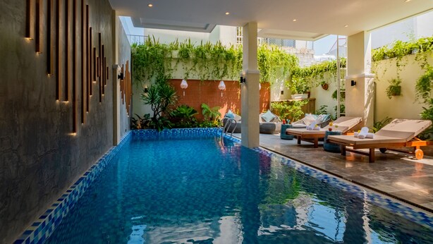 Een modern binnenzwembad met een helder zwembad, lounge fauteuils en wanden met een verticale tuin.