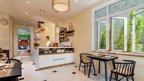 Een moderne keuken met witte kasten, een centraal eiland en een eethoek met een tafel en stoelen.