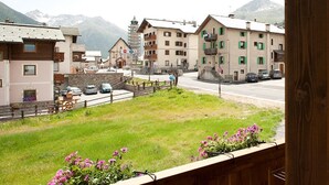 A view of a town with buildings, a road, and mountains in the background.