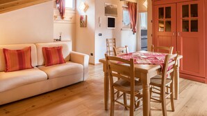 A cozy living room with a sofa, wooden dining table, and chairs.