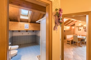 A wooden interior with a skylight, a bathroom with two toilets, and a dining area with a table and chairs.