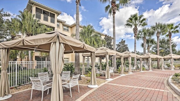 A resort with outdoor seating areas, palm trees, and a brick pathway. - Luxurious River Views, Resort Amenities, Lrg 3 Bed, 2 Bath, Corner Unit, 2100 SF (Palm Coast)
