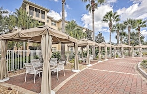A resort with outdoor seating areas, palm trees, and a brick pathway.