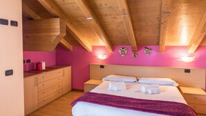 A bedroom with a wooden ceiling, pink walls, a bed with white linens, a bedside table, and a nightstand. - Casa Azzurra with Mountain View, Wi-Fi, Balcony & Garden; Parking Available (Livigno (SO))
