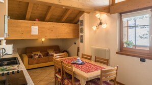 A wooden interior with a dining table, chairs, a sofa, a radiator, and a window with a view. - Casa Azzurra with Mountain View, Wi-Fi, Balcony & Garden; Parking Available (Livigno (SO))