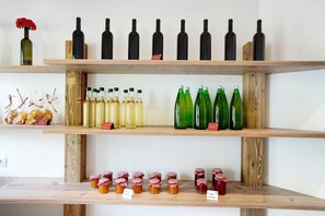 Una repisa de madera con botellas y frascos varios, incluyendo vino y miel.