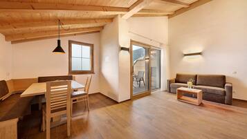 Une pièce avec un plafond en bois, une table à manger avec des chaises, un canapé et une petite table basse.