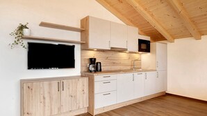 Een moderne keuken met houten kastjes, een ingebouwde magnetron en een koffiezetapparaat.