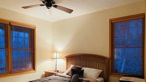 A bedroom with a bed, a nightstand, a lamp, a ceiling fan, and a crib. - NEW! STUNNING Lake Harmony Mountain House Golfing! (Lake Harmony)