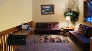 A cozy living room with a sofa, a small table, a lamp, and a painting on the wall. - NEW! STUNNING Lake Harmony Mountain House Golfing! (Lake Harmony)