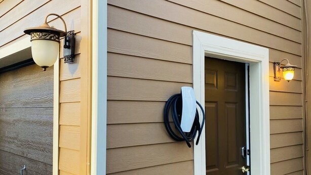A house with a brown siding exterior, a white door, and two wall-mounted light fixtures. - NEW! STUNNING Lake Harmony Mountain House Golfing! (Lake Harmony)