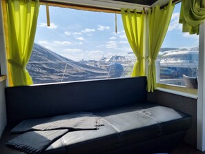 Ein Fenster mit Vorhängen, ein Sofa und Blick auf Boote.