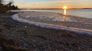 Una playa de guijarros con un atardecer sobre el agua.