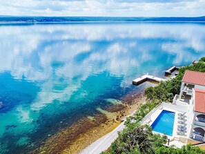 A coastal property with a swimming pool, a dock, and a clear view of the sea.