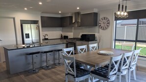 Una cocina moderna con una isla central, taburetes de bar y una mesa de comedor con sillas.