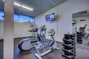 A gym with exercise equipment, a television, and a mirror. - Renovated 3BR Harbor Towers: Pools, Tennis & Beach (Siesta Key)